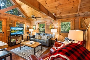 A cozy cabin interior with a wooden ceiling, a television, a sofa, a coffee table, and a fireplace. - Cabin at Oak Ridge - Hot Tub, Arcade Game, Firepit + 2 Mi from Downtown Gatlinburg (Gatlinburg)