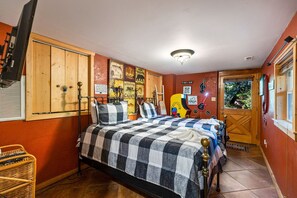 Ein Schlafzimmer mit einem Bett, einem Holzschrank, Wandbildern und einer Tür mit Fenster.