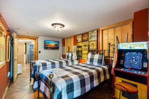 A room with two beds, a Pac-Man arcade machine, and a television on the wall. - Cabin at Oak Ridge - Hot Tub, Arcade Game, Firepit + 2 Mi from Downtown Gatlinburg (Gatlinburg)