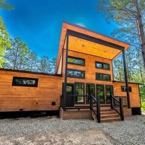 Ein modernes, zweistöckiges Holzhaus mit einer zentralen Treppe und großen Fenstern.