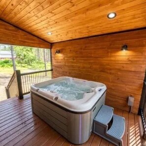 Une terrasse en bois avec un jacuzzi et des marches menant à celui-ci.