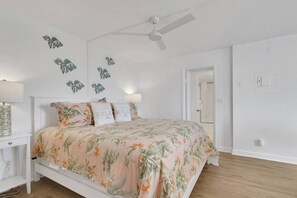 A bedroom with a bed, a nightstand, a ceiling fan, and a door. - Fresh Coastal-Style Studio | 10th Floor Bay & Gulf Views | Steps to Bonita Beach | Free Parking (Bonita Springs)