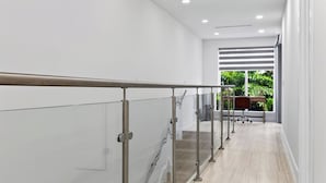 Un interno moderno con ringhiera in vetro, una scrivania in legno e vista su spazi verdi.