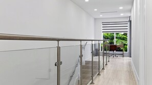 Ein modernes Interieur mit Glastrennwand, einem Holztisch und Blick auf Grünflächen.
