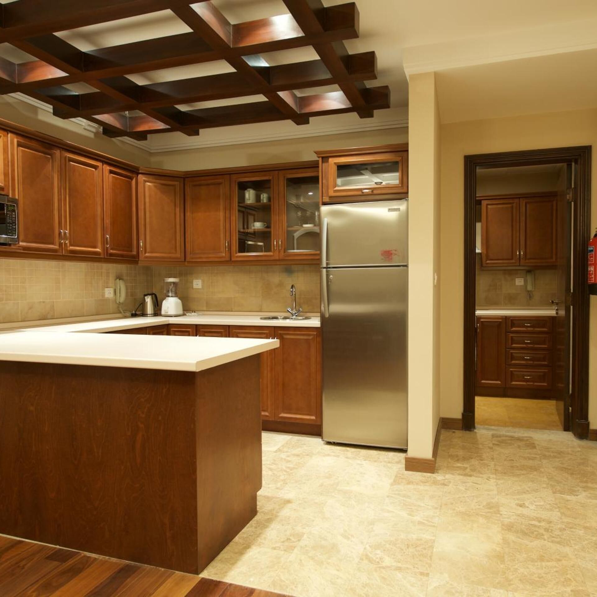 A kitchen with wooden cabinets, a stainless steel refrigerator, and a large island.