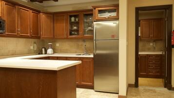 A kitchen with wooden cabinets, a stainless steel refrigerator, and a large island.