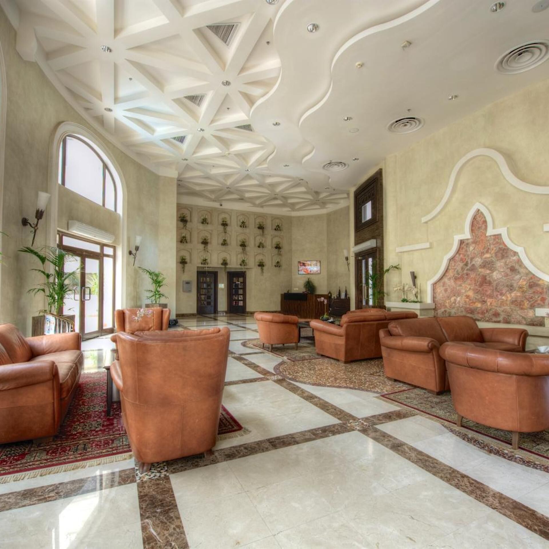 A spacious lobby with a high ceiling, large windows, and a patterned floor.