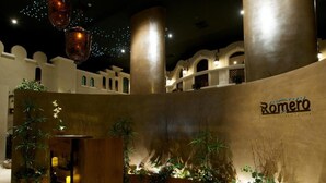 Una hall d'hotel con una struttura centrale in legno, un pavimento decorato e una parete con il nome 'Romeró'.