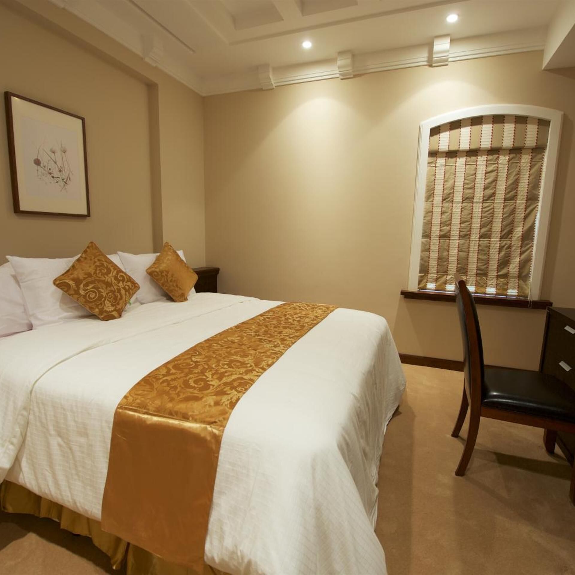 A hotel room with a large bed, a desk, and a chair.
