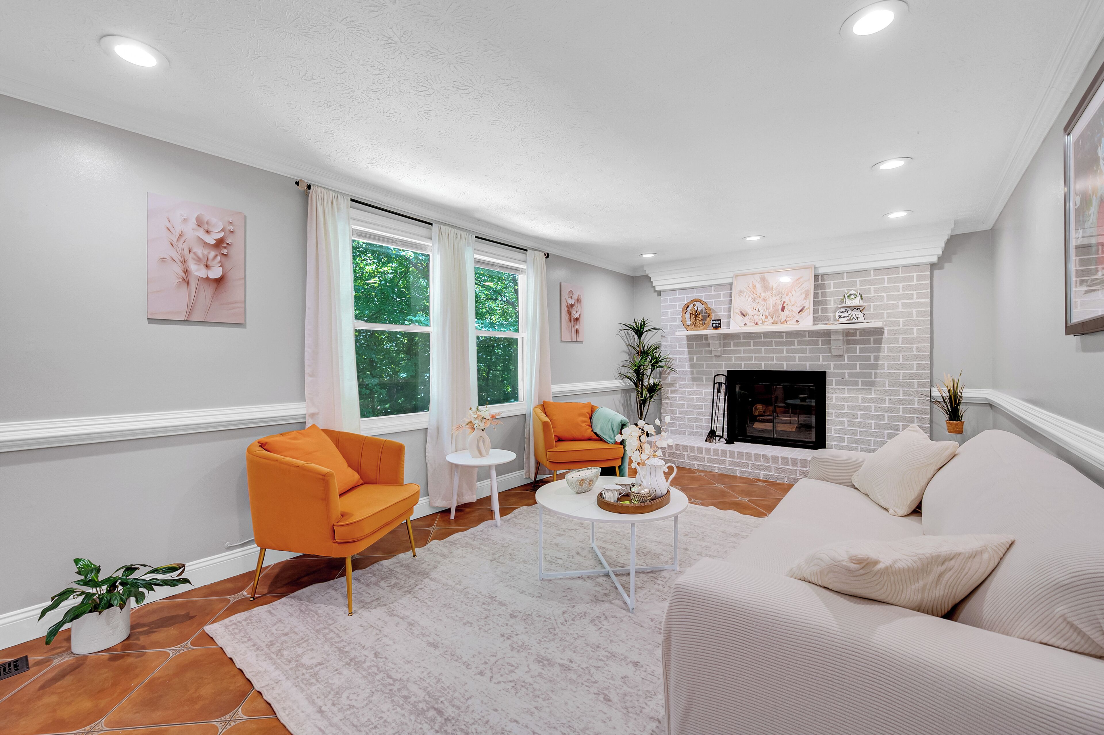 Uma sala de estar moderna com lareira, um sofá, uma poltrona laranja e uma mesa de centro.