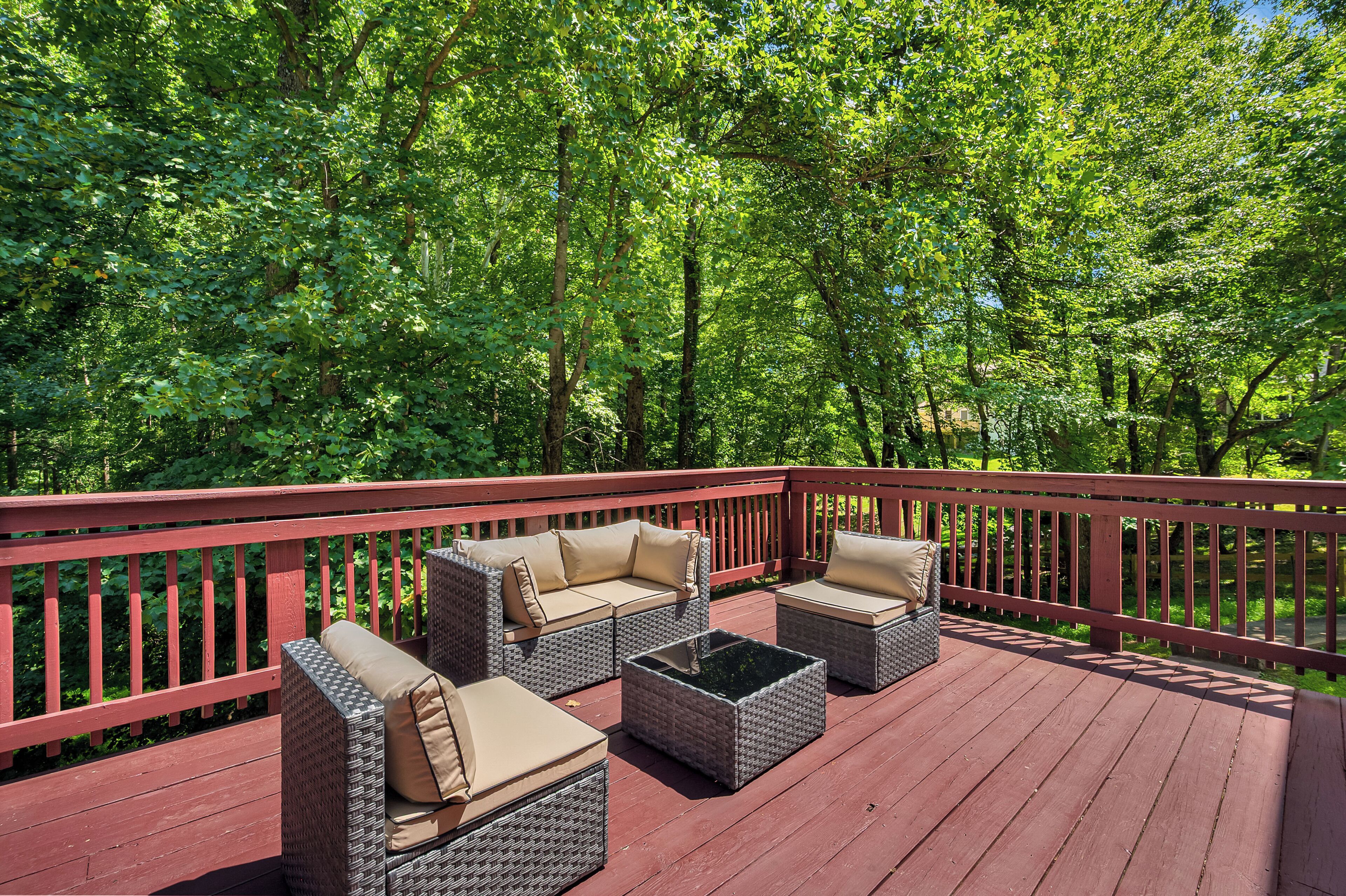 A deck with wicker furniture and a red railing.