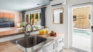 A modern kitchen with a stainless steel sink, a wooden countertop, and a view of the outdoors through a window with blinds. - Lux WPB Oasis with Heated Pool/Spa + GameRoom – Sleeps 12! (West Palm Beach)