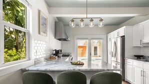 A modern kitchen with white cabinets, a marble island, and a stainless steel refrigerator. - Lux WPB Oasis with Heated Pool/Spa + GameRoom – Sleeps 12! (West Palm Beach)