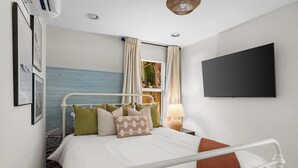 A modern bedroom with a bed, a TV, and a window with curtains. - Lux WPB Oasis with Heated Pool/Spa + GameRoom – Sleeps 12! (West Palm Beach)