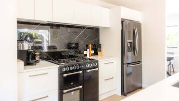 A modern kitchen with white cabinetry, a black stove, and a stainless steel refrigerator.