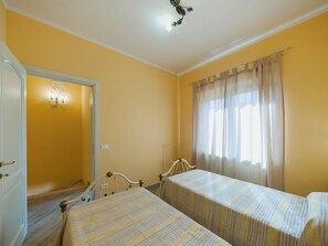 Una camera da letto con due letti singoli, un armadio, uno specchio e una finestra con tende.