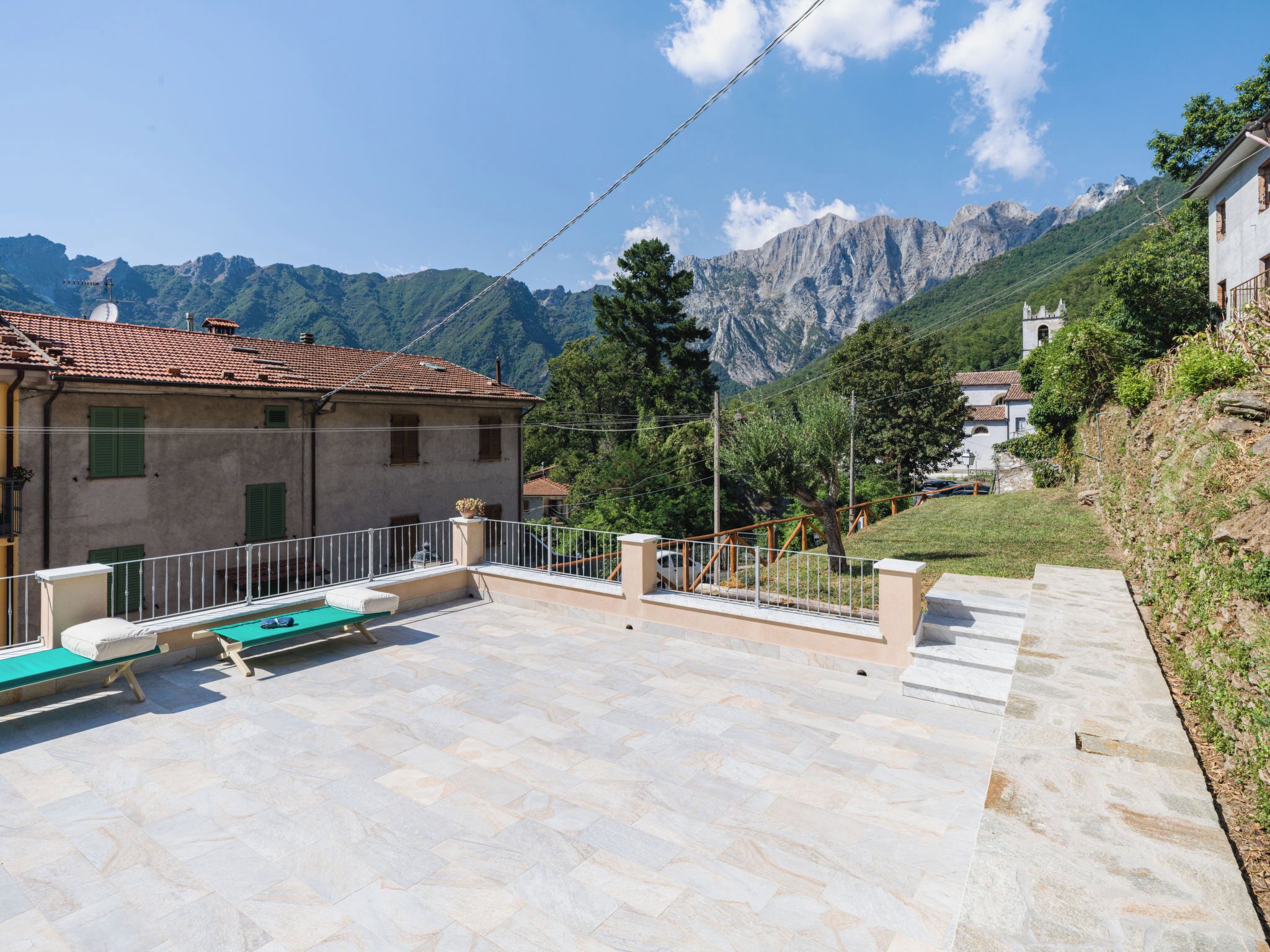 Eine Villa mit Terrasse, Gartenmöbeln und Bergblick.