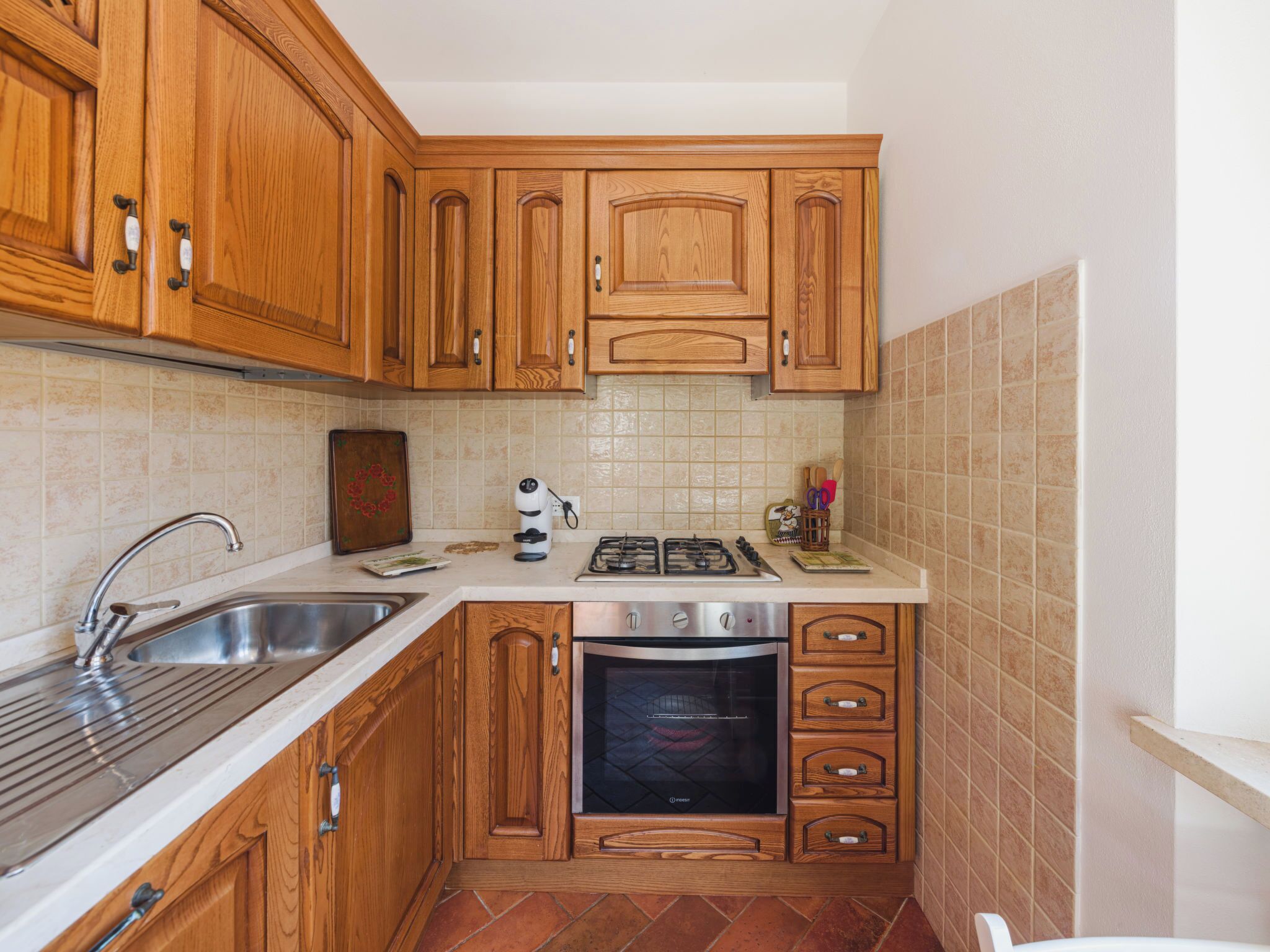 Una cucina compatta con mobili in legno, un lavello in acciaio inossidabile, un piano cottura a gas e un forno integrato.