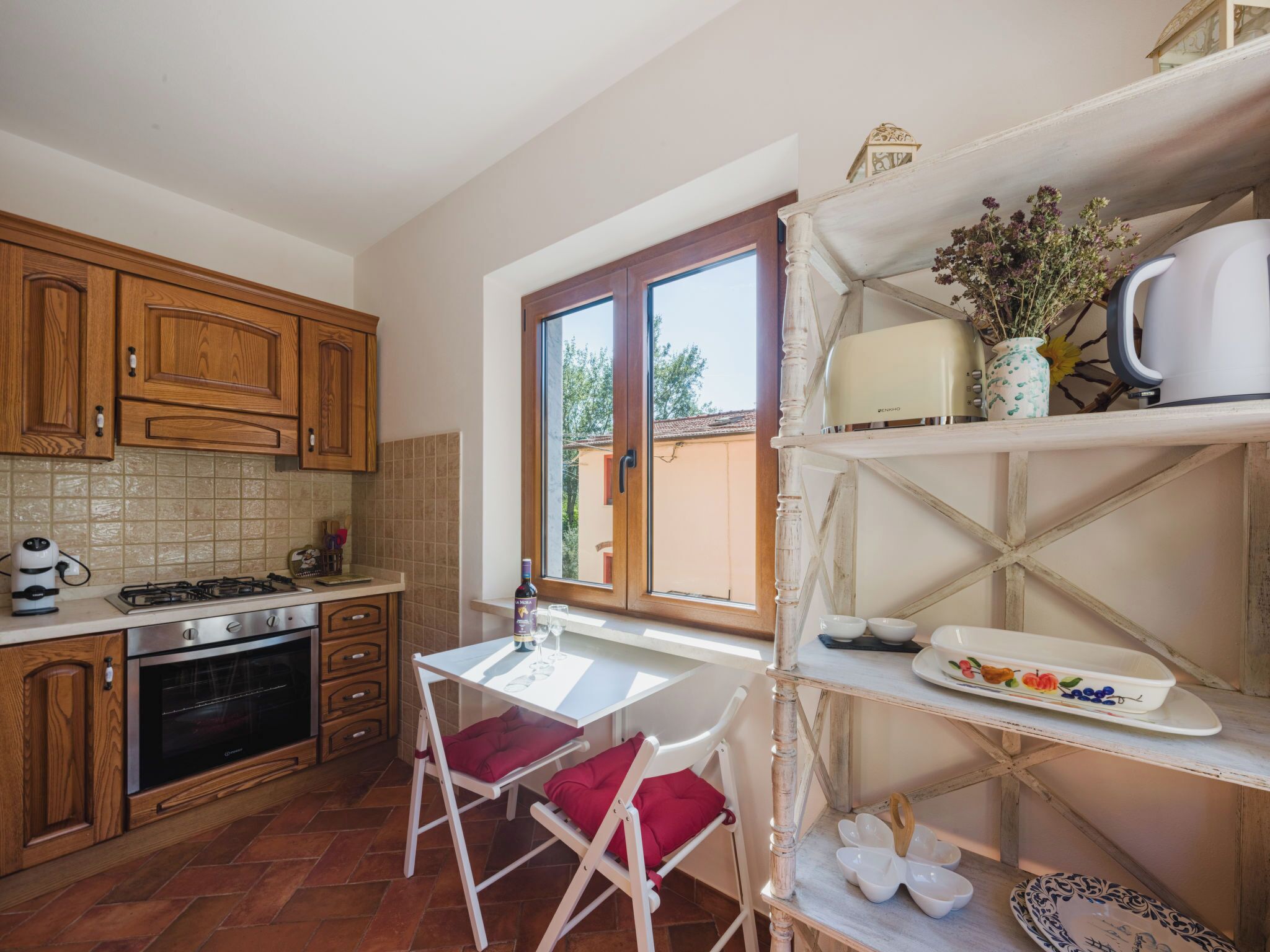 Una cucina con mobili in legno, un fornello e un'area pranzo con tavolo e sedie.