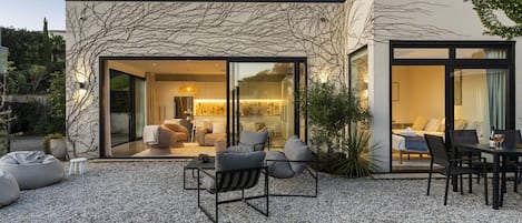 Una casa moderna con patio, mobiliario exterior y una mesa de comedor.