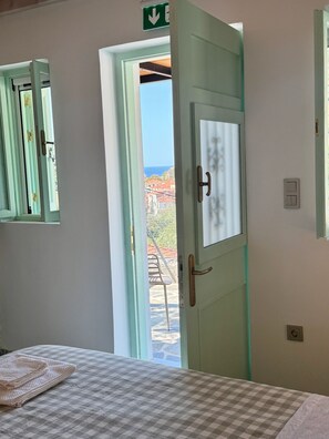 A room with a bed, a window with a view, and a door leading outside.