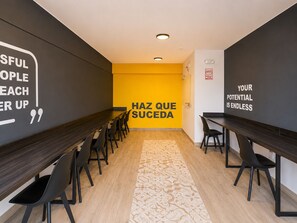 Una sala de reuniones moderna con una larga mesa y sillas, citas motivacionales en las paredes y una alfombra estampada.