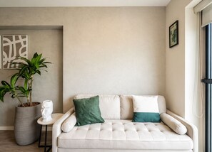A neutral-toned living area with a sofa, a potted plant, and a small table. - City Nest in Jesús María (Jesús María)