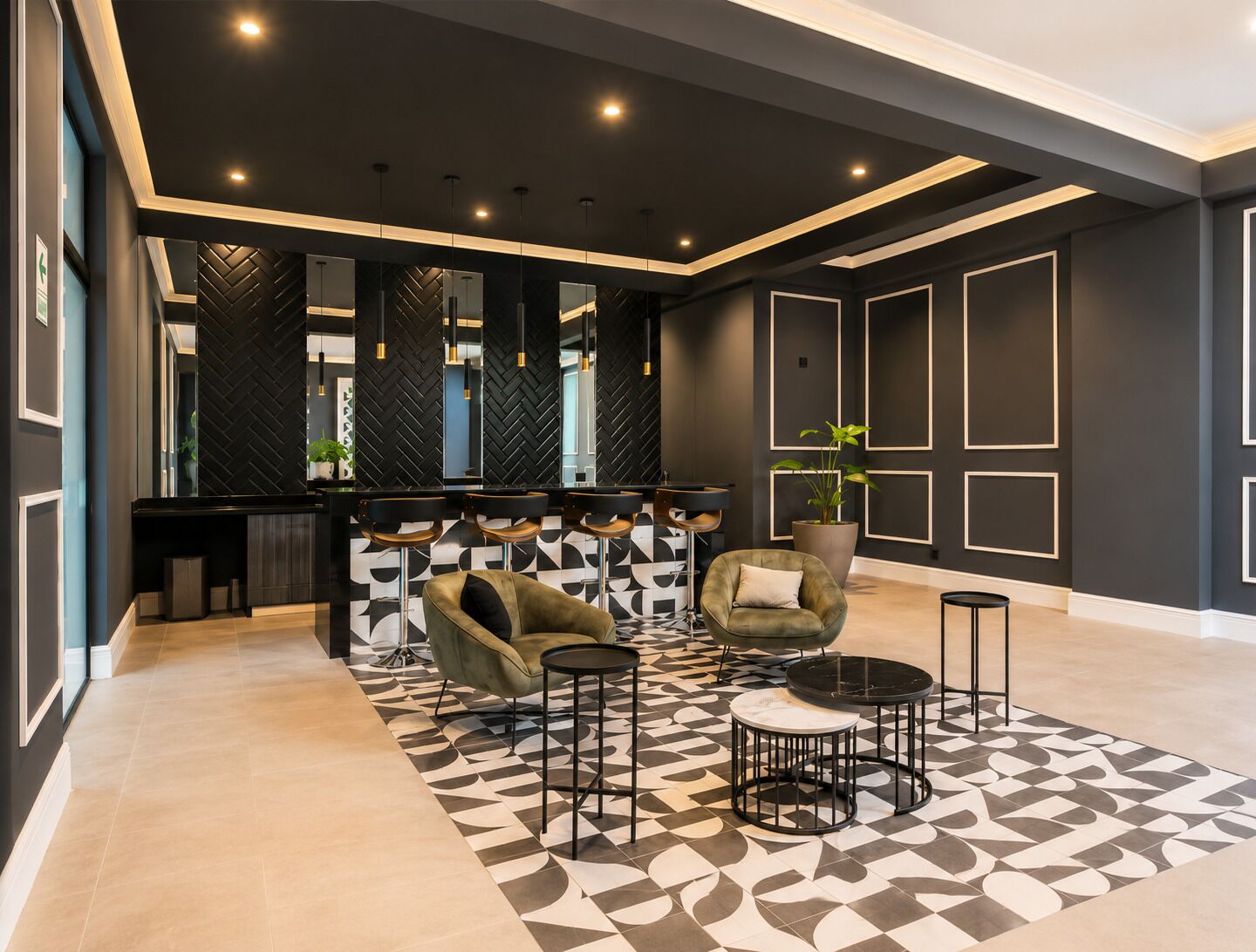A modern lobby with a bar area, two armchairs, a round table, and a patterned floor.