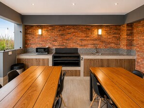A modern outdoor kitchen with a brick wall, a built-in microwave, and a grill. - City Nest in Jesús María (Jesús María)