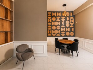 A dining area with a wooden table and black chairs, a grey upholstered chair, and a wall with a geometric wooden panel design. - City Nest in Jesús María (Jesús María)