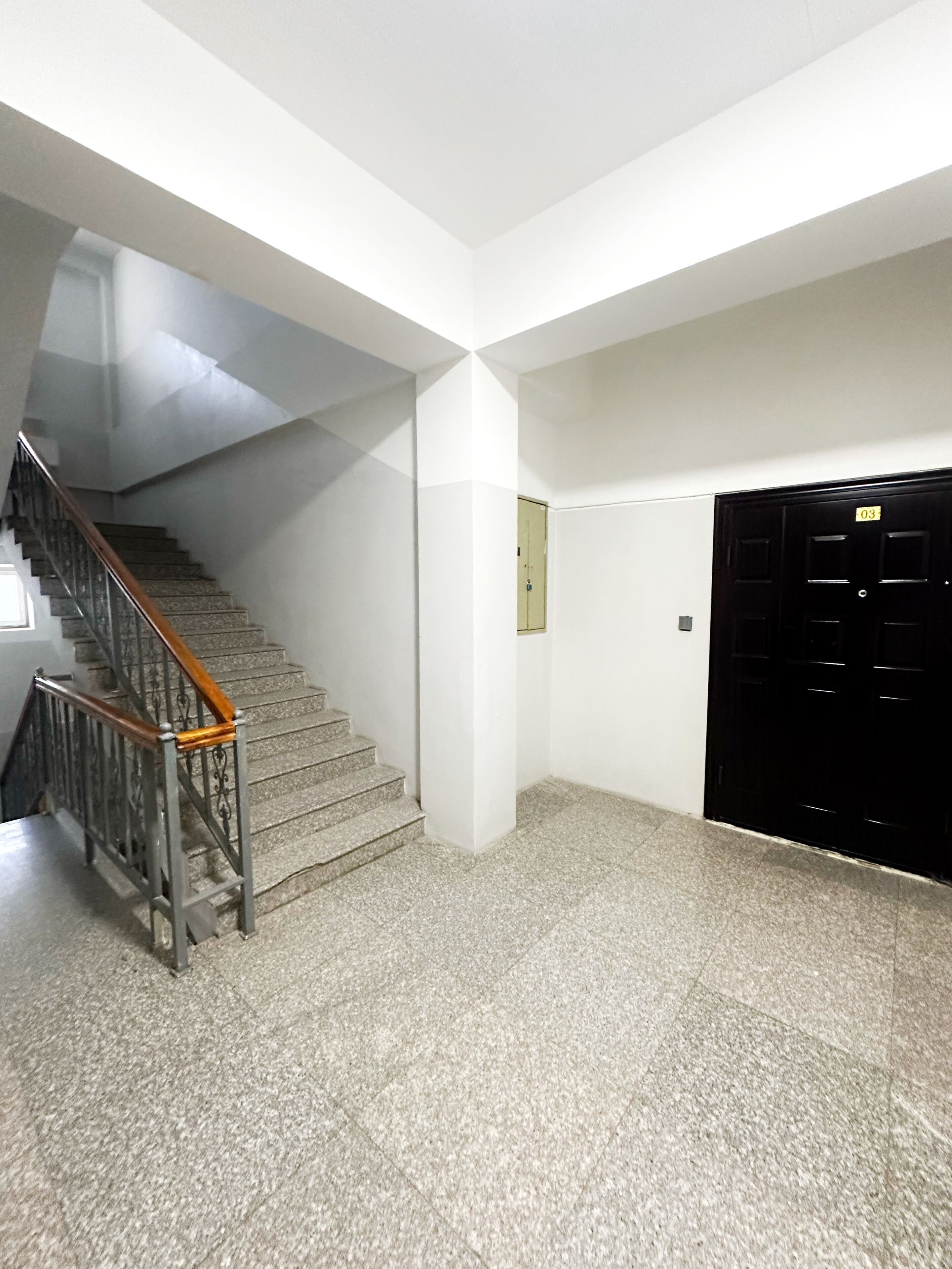 A staircase with metal railings and a carpeted floor leading to a door marked with the number 03.