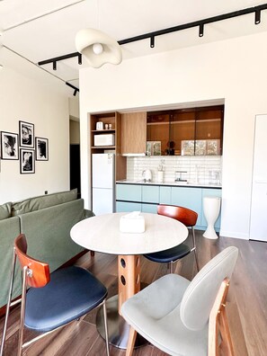 A modern kitchen with a microwave, toaster, and cabinets. There is a dining area with a round table and chairs. - Haven III- Quiet Luxury next to Shangri-La UB (Ulaanbaatar)