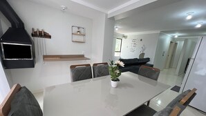 A modern dining area with a glass table, grey upholstered chairs, and a potted plant. - Family apartment with great comfort and a great location in Toledo, Paraná. (Toledo)