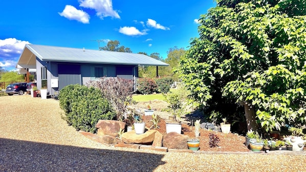 A modern house with a sloped roof, surrounded by a gravel driveway and a variety of potted plants.