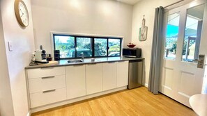 A kitchen with a window, a microwave, and a clock on the wall.