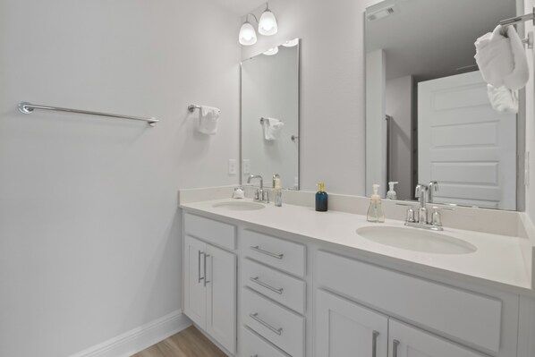A modern bathroom with two sinks, a mirror, and a towel rack.