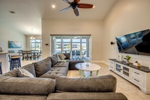 Un salon spacieux avec un canapé d’angle, un téléviseur à écran plat et un ventilateur de plafond.