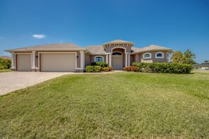 A two-story house with a front garage, a covered entryway, and a well-maintained lawn. - Fantastic 4-bedroom house with Heated Saltwater Pool & Spa (Cape Coral)