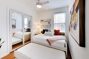 Ein Schlafzimmer mit Bett, Nachttisch, Lampe und Deckenventilator.