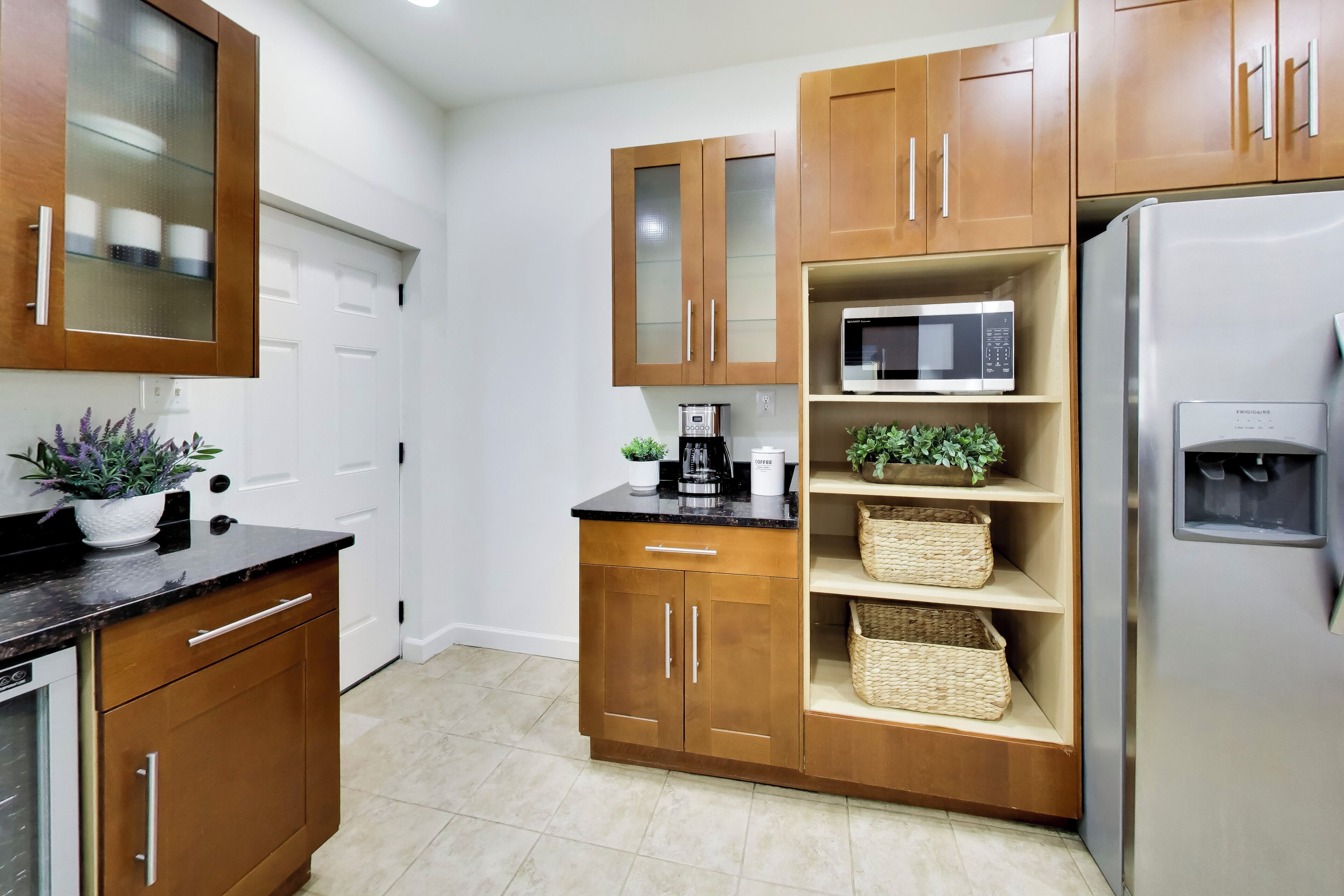 Una cocina moderna con armarios de madera, microondas integrado, cafetera y refrigerador.