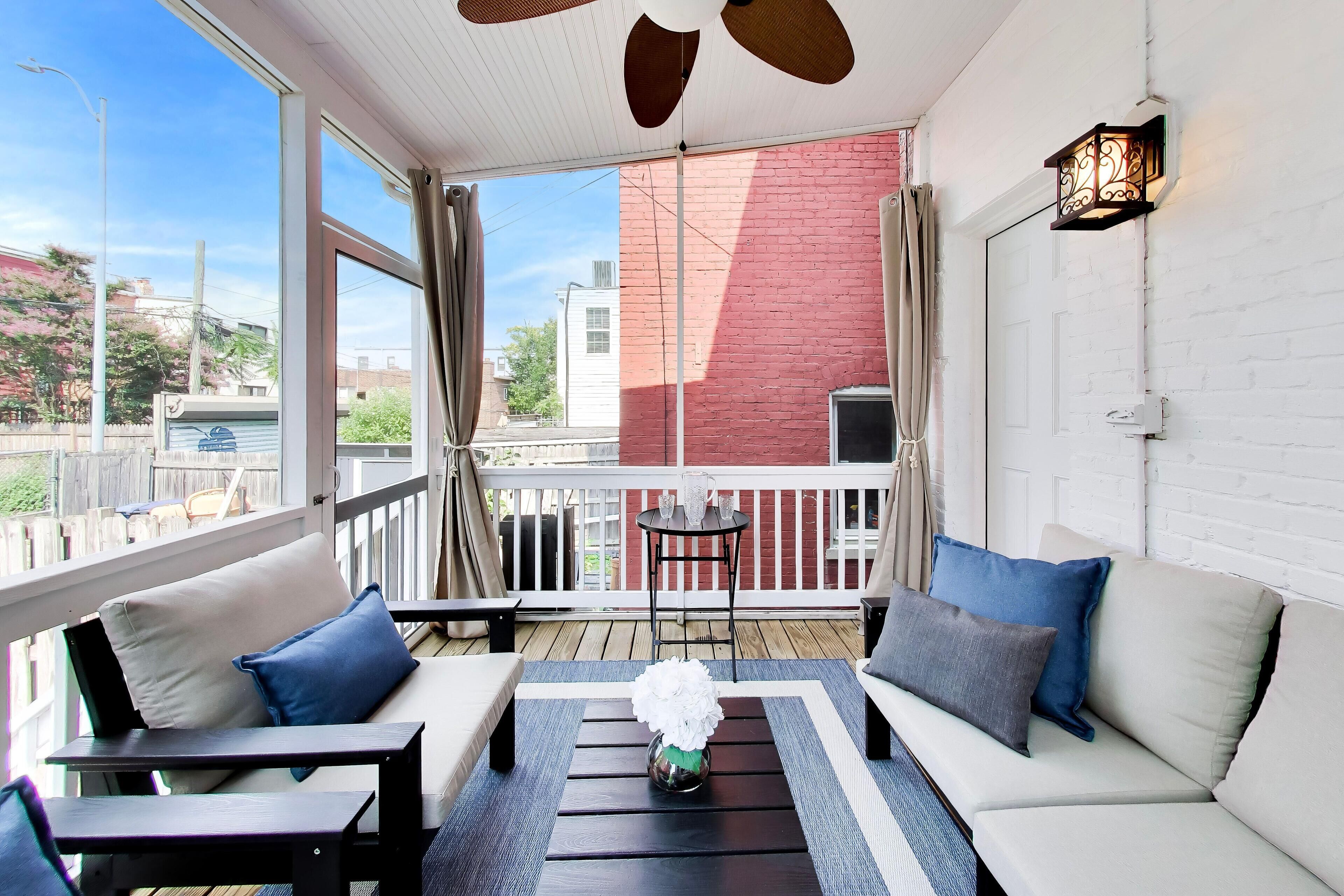 A balcony with a white sofa, two armchairs, a small table, and a decorative vase.