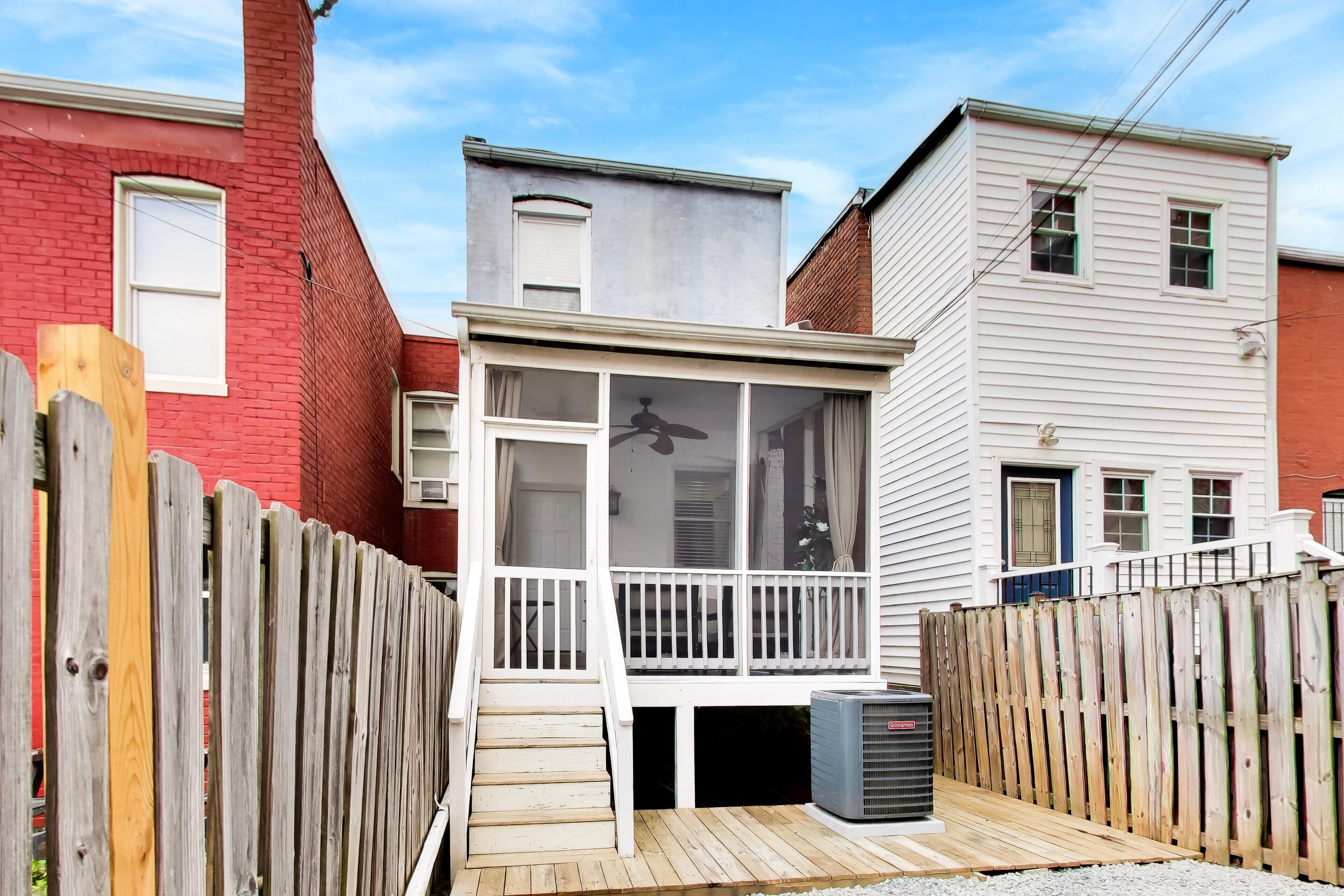 A residential property with a wooden deck, a small porch, and a visible air conditioning unit.