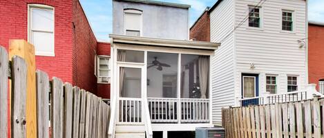 A residential property with a wooden deck, a small porch, and a visible air conditioning unit.