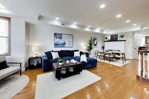 Ein modernes Wohnzimmer mit einem blauen Sofa, einem Couchtisch und einem Essbereich mit Stühlen.