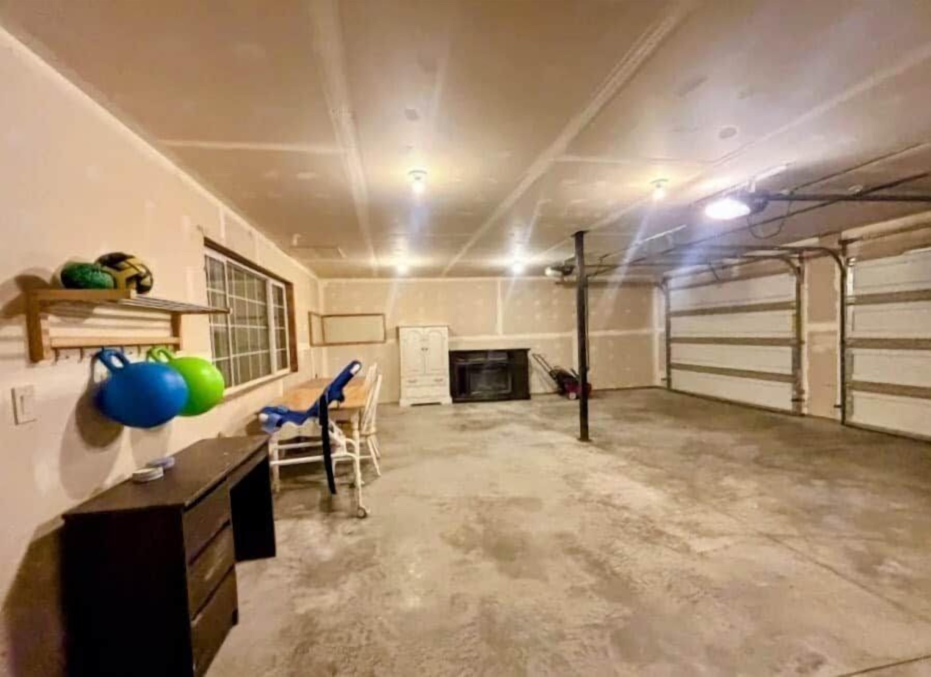 A garage with a concrete floor, a white door, and a fireplace.