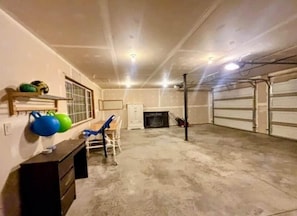 Un garage avec un sol en béton, une porte blanche et une cheminée.