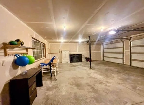 A garage with a concrete floor, a white door, and a fireplace.