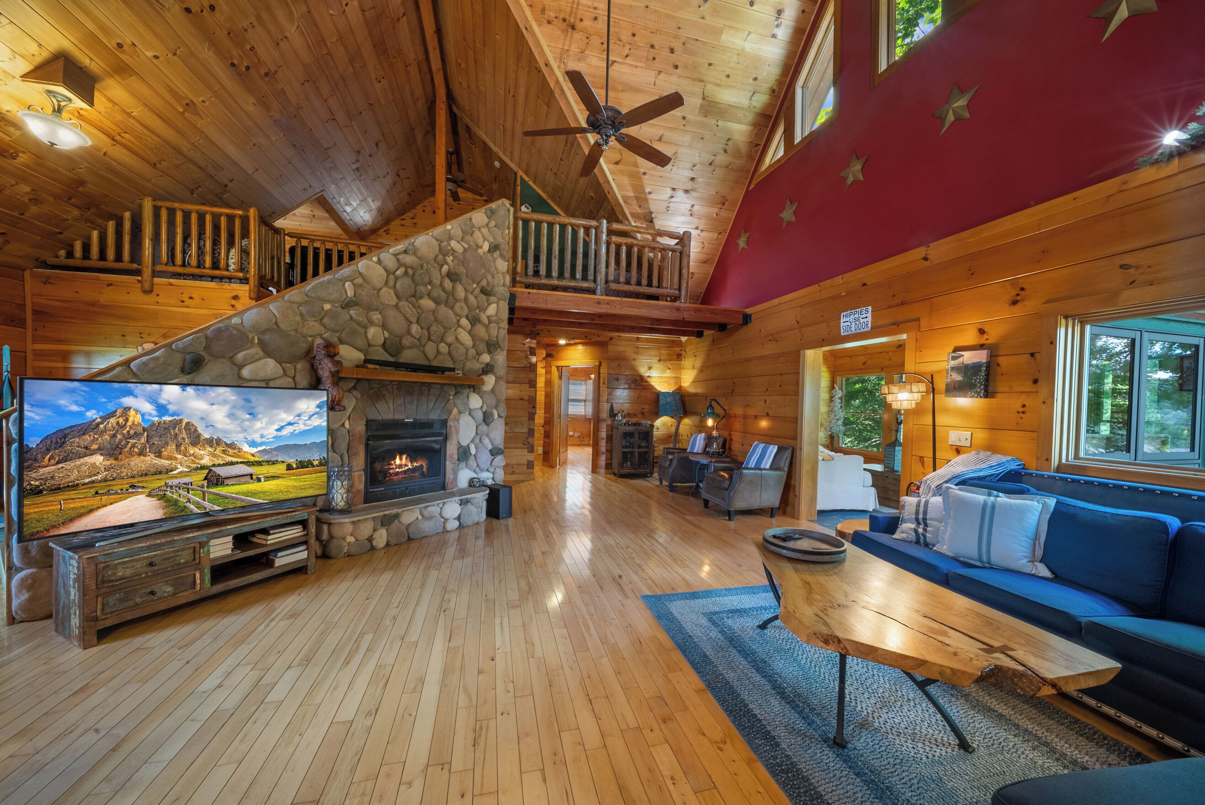 A wooden interior with a stone fireplace, a television, and a sofa.
