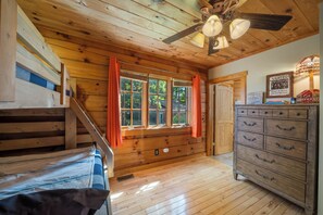 A wooden cabin interior with a bed, dresser, and window with curtains. - Spacious Family Cabin Near Downtown Boone (Boone)