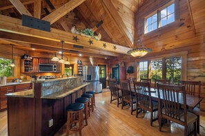 A spacious kitchen with a central island, bar stools, and a dining area with wooden tables and chairs. - Spacious Family Cabin Near Downtown Boone (Boone)
